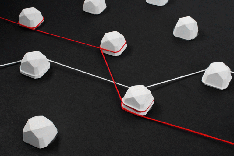 White faceted spheres connected by red and white strings on a black surface, illustrating a network graph with nodes and links.
